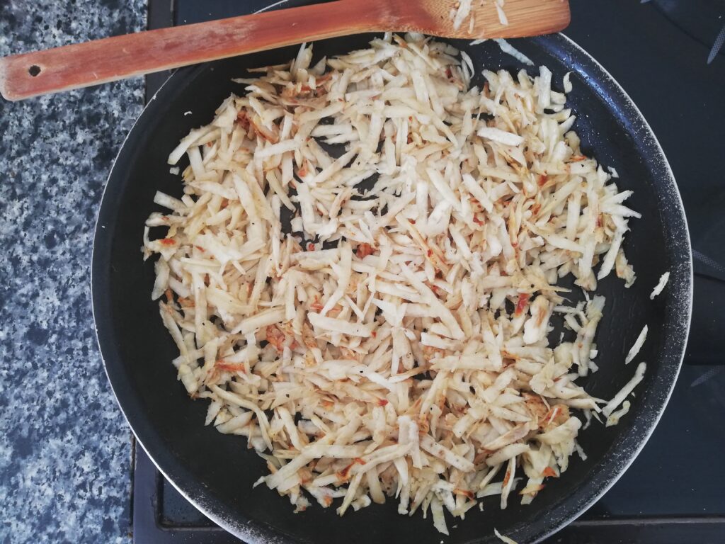 shredded sweet potatoes cooking in a skillet