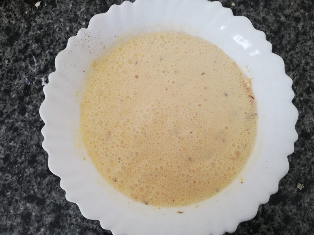 mixed eggs milk cream and cheese in a white bowl