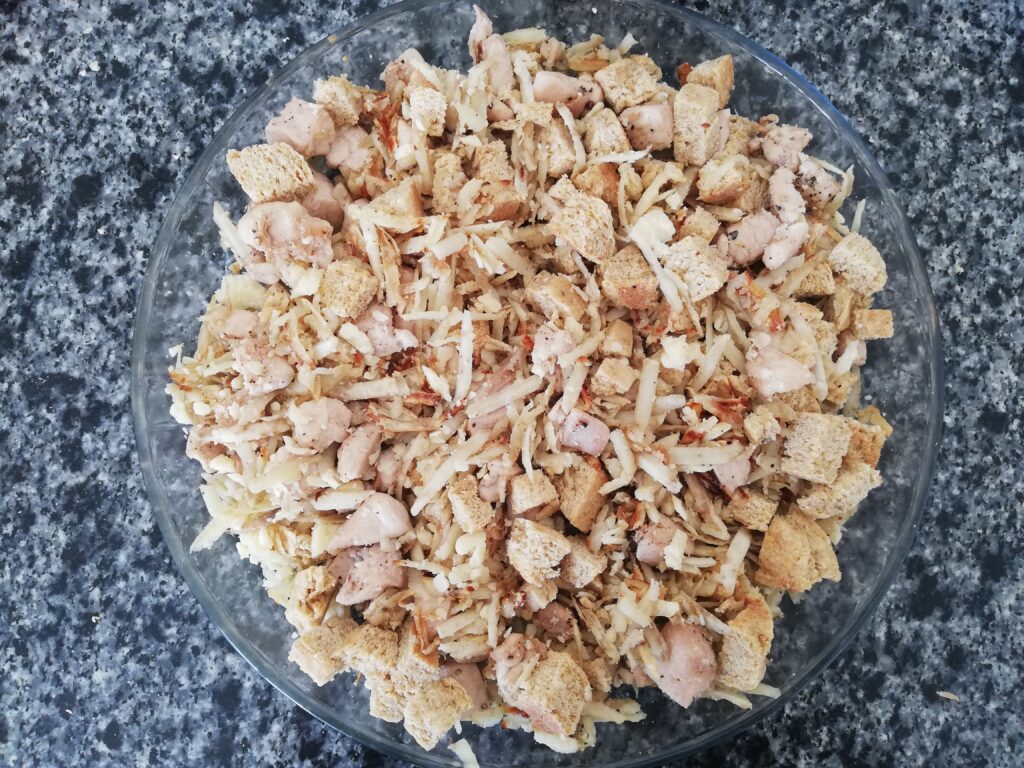 cubed sourdough bread subed chicken and shredded sweet potatoes in a casserole dish