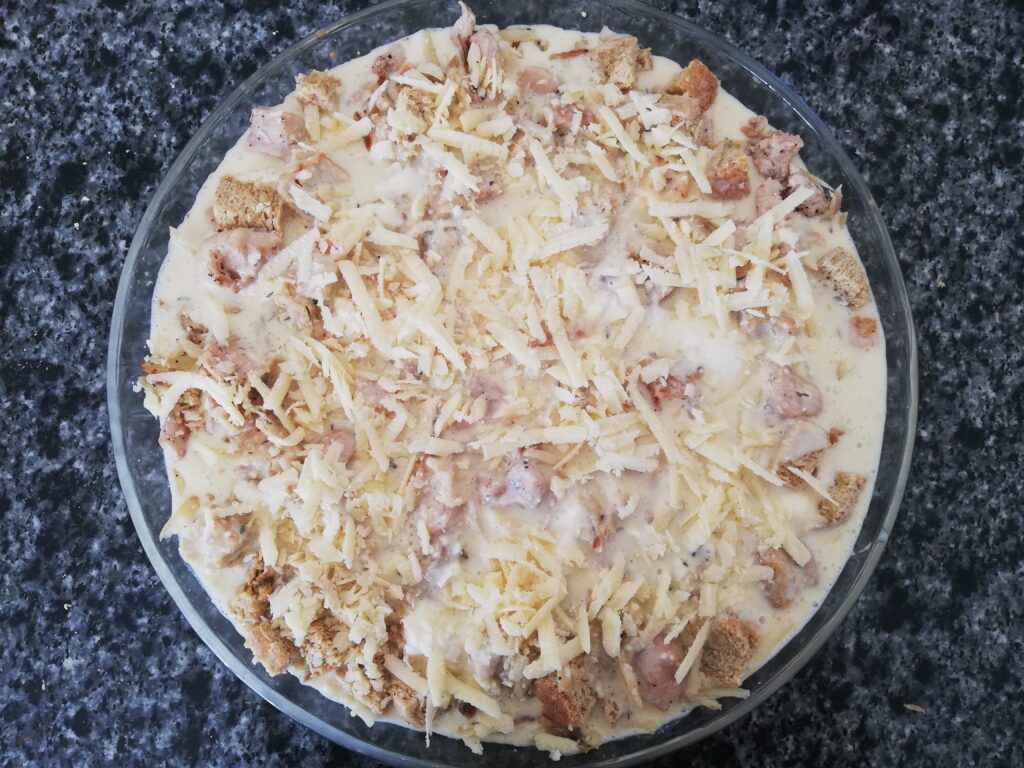 uncooked breakfast casserole with shredded cheese on top of a marble countertop