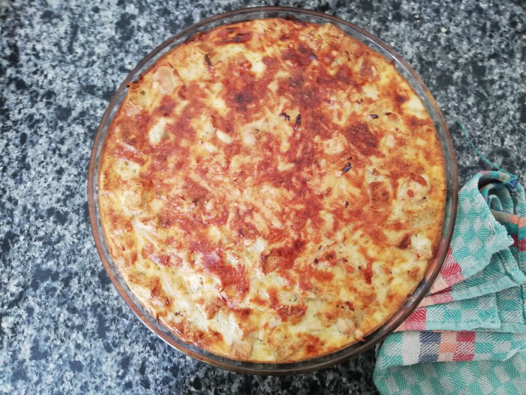 sourdough breakfast casserole in a round glass dish on top of a marble countertop