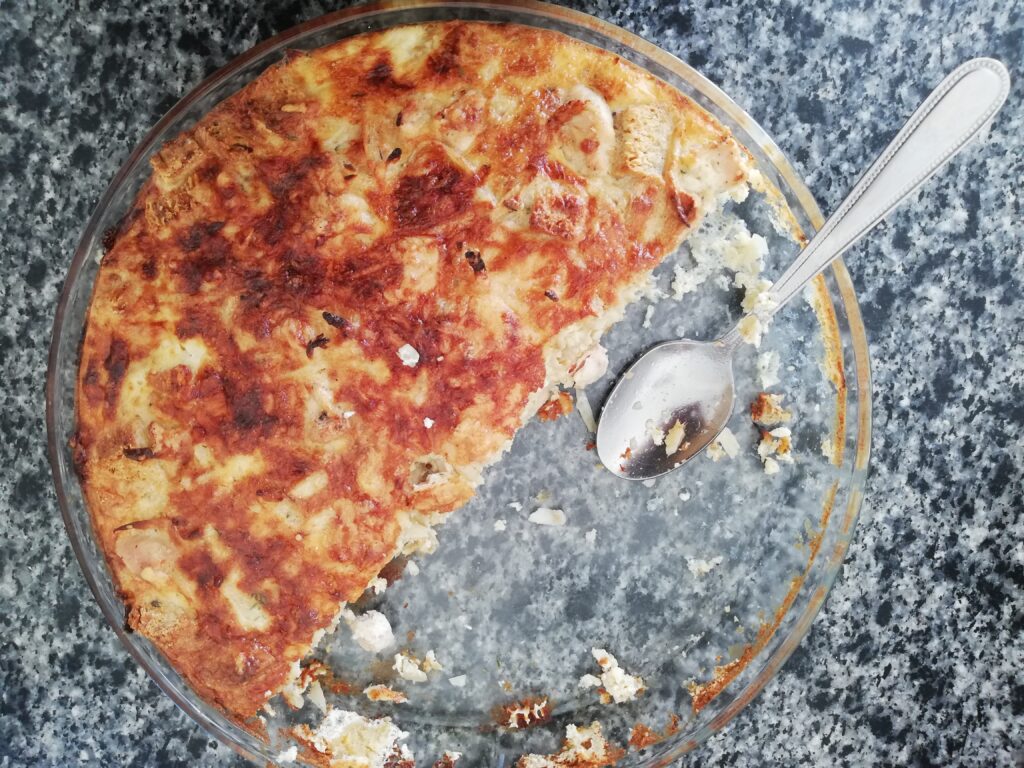 half of a sourdough breakfast casserole left in a glass dish on top of a marble countertop