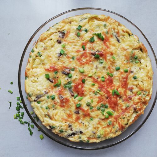 round glass dish with crustless quiche with some chives scattered on the side