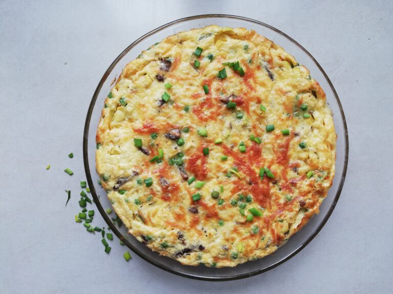round glass dish with crustless quiche with some chives scattered on the side