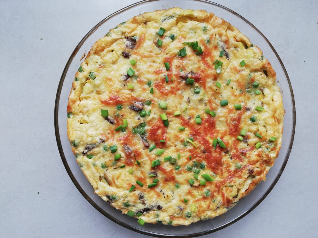 round glass pie dish with crustless quiche with chives scattered on top