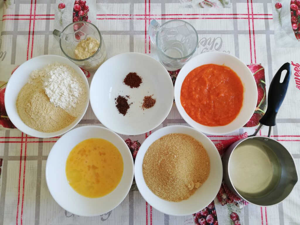 a cup of sourdough starter a bowl of spices a cup of water a bowl of pumpkin puree a saucepan of melted coconut oil a bowl of brown sugar a bowl of whisked eggs a bowl of flour