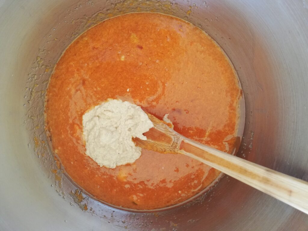 a bowl of pumpkin puree eggs and sugar with a dollop of sourdough starter in the middle and a wooden spoon