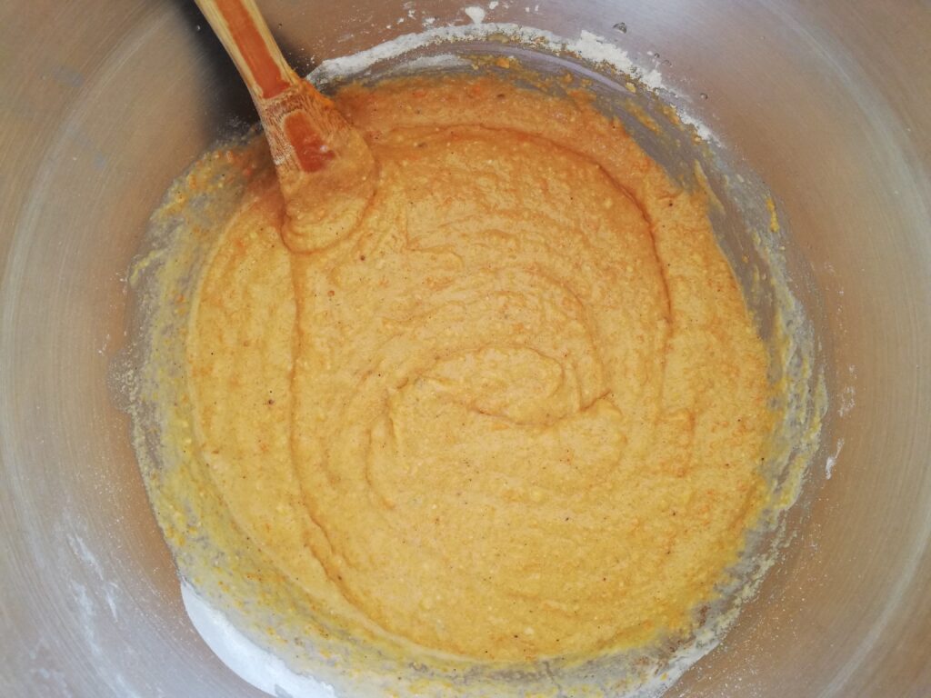 metal bowl with sourdough pumpkin muffin batter and a wooden spoon