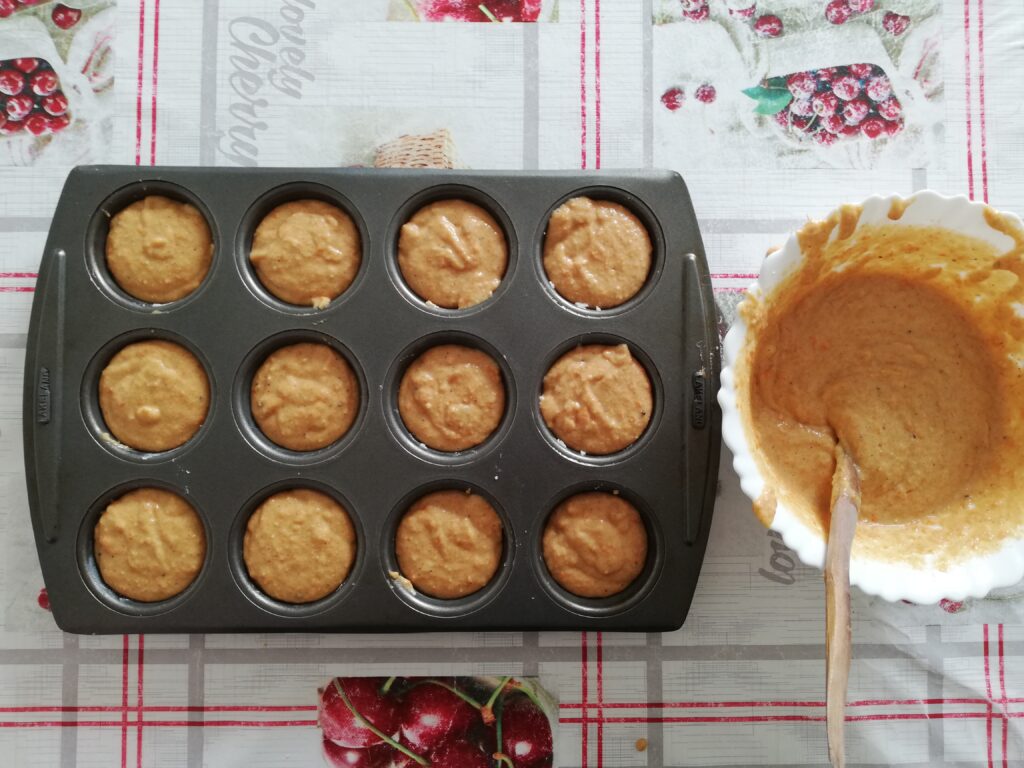 muffin pan and a white bowl with sourdough pumpkin muffin batter