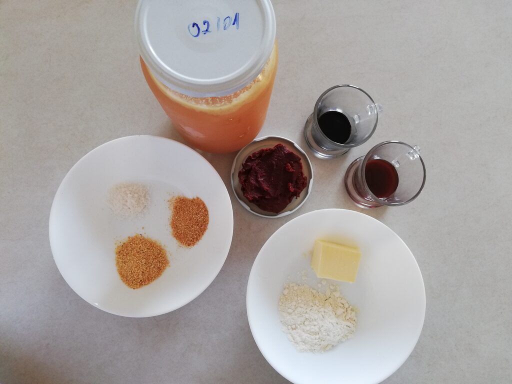 a jar of stock a lid of tomato paste a cup with a spoon of molasses a cup with a spoon of soy sauce a bowl with butter and white flour a bowl with onion powder garlic powder and salt