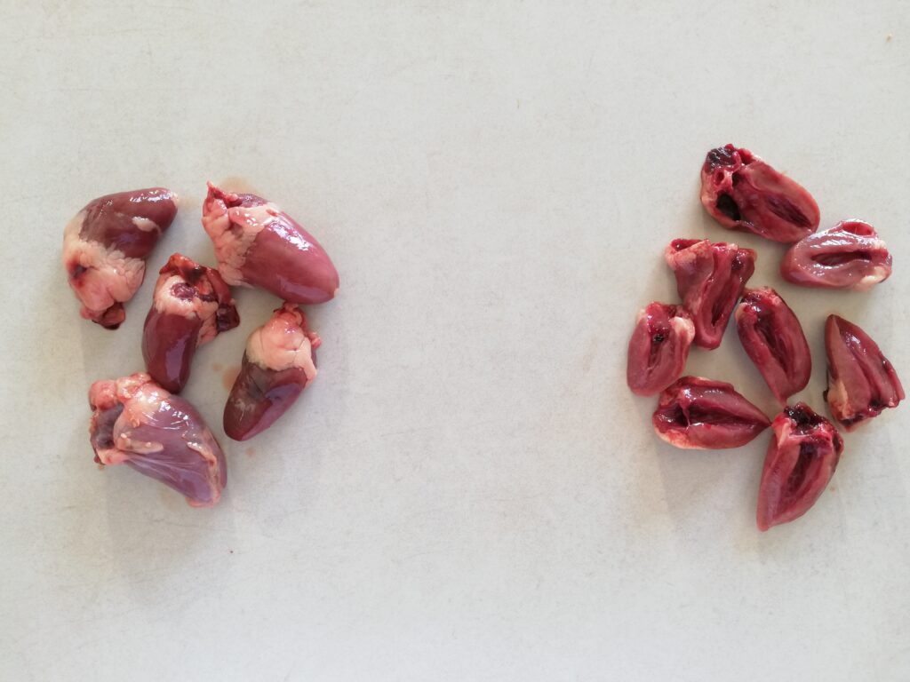 whole chicken hearts on the left, halved chicken hearts on the right on a marble countertop