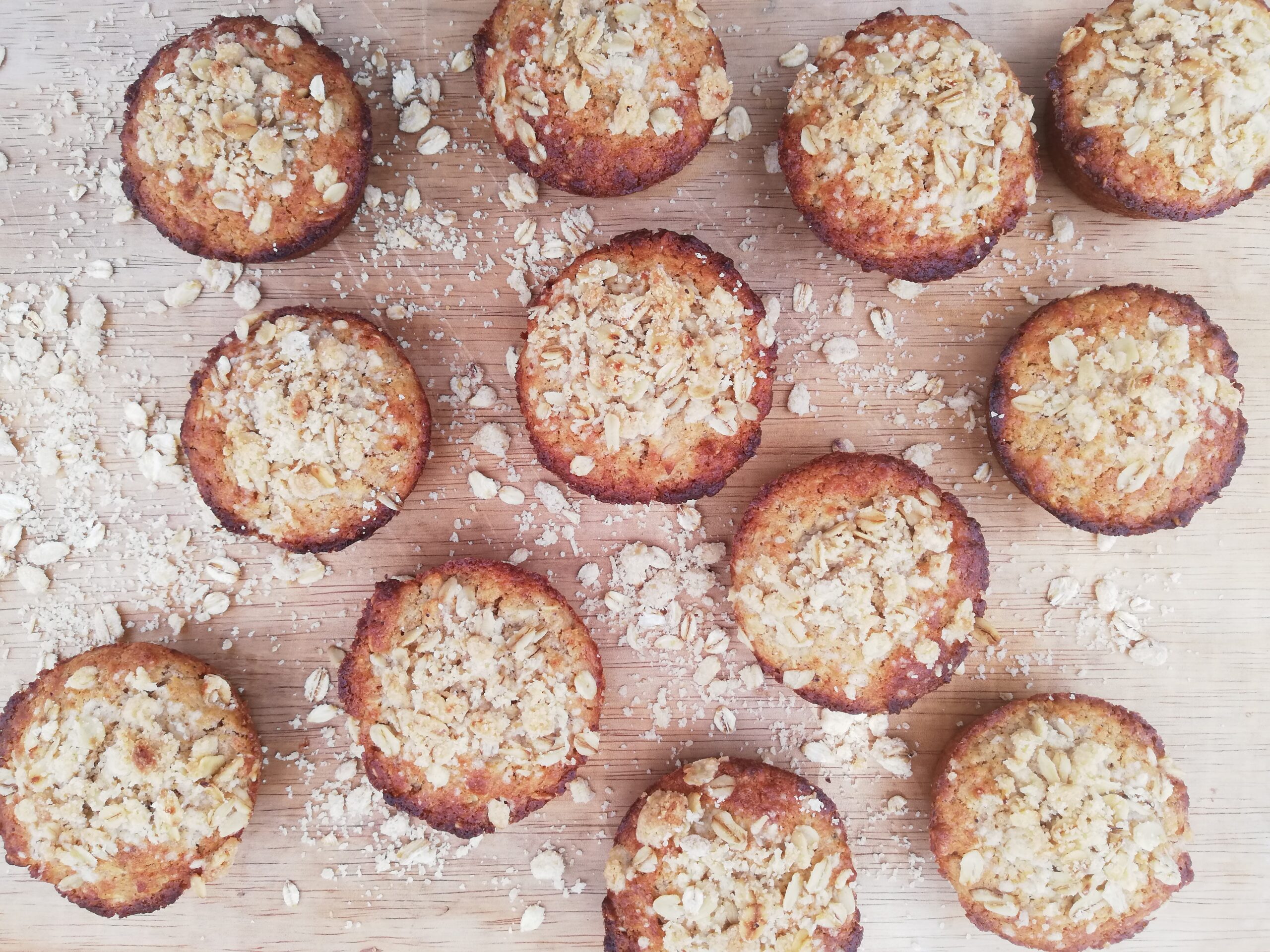 sourdough oatmeal muffins on a wooden board with oatmeal crumb topping sprinkled around