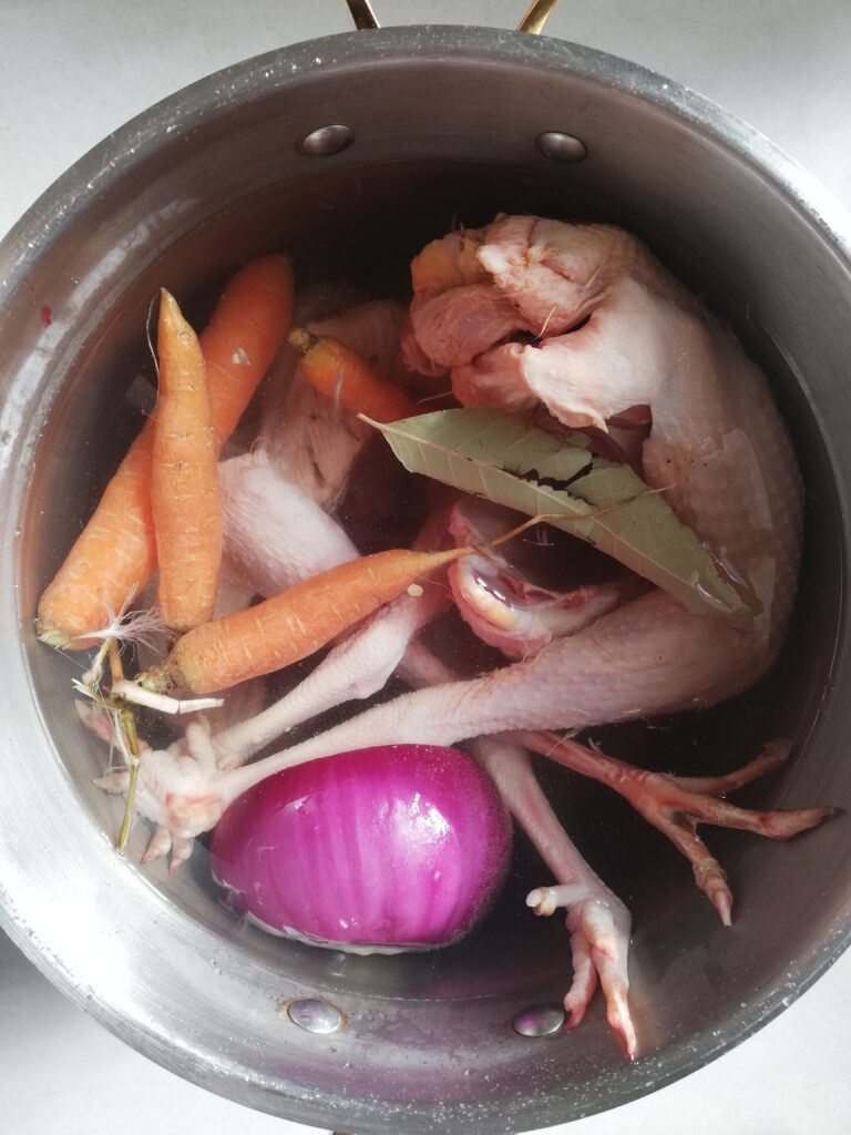 metal pot with chicken carrots onion and bay leaf