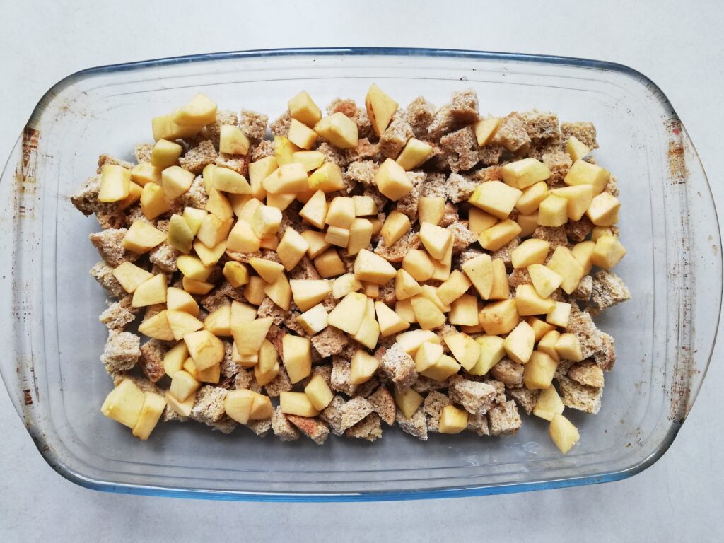 glass casserole dish with cubed sourdough bread and chopped apples