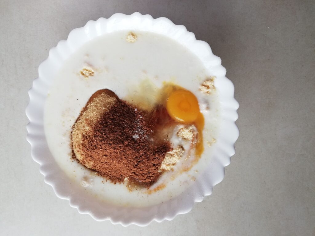 Adding sour milk, egg, and spices to flour and butter to make the sourdough gingerbread muffin batter