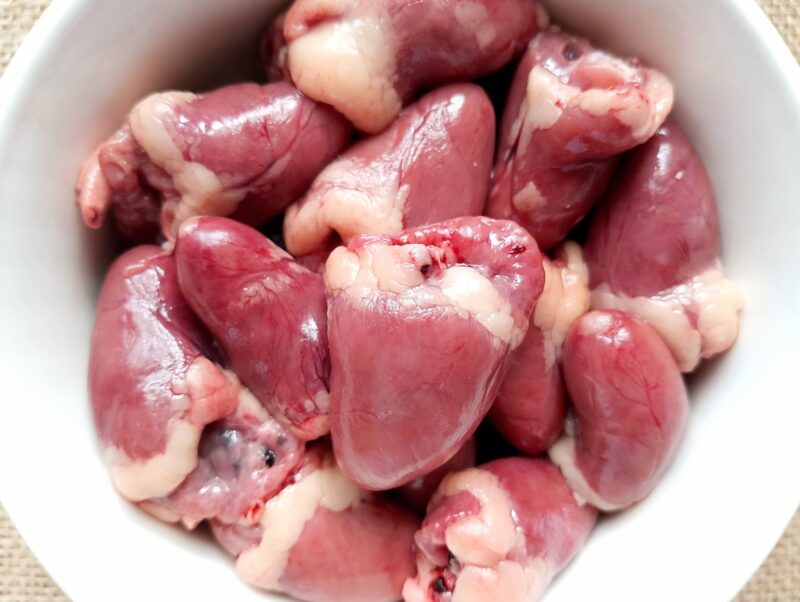 Raw cleaned chicken hearts in a bowl, ready for cooking