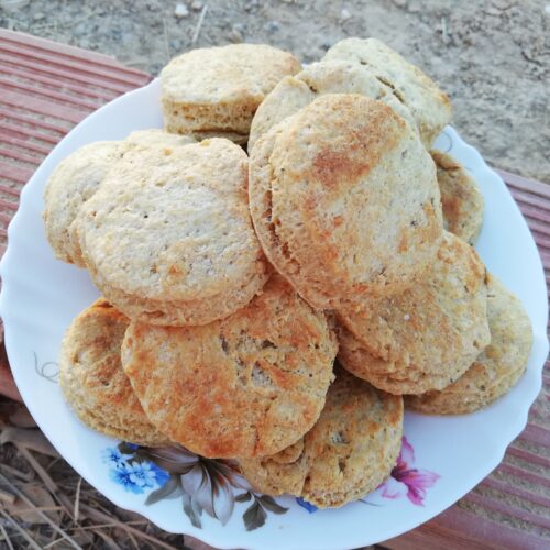 sourdough tallow biscuits on a white plate standing on top of some bricks