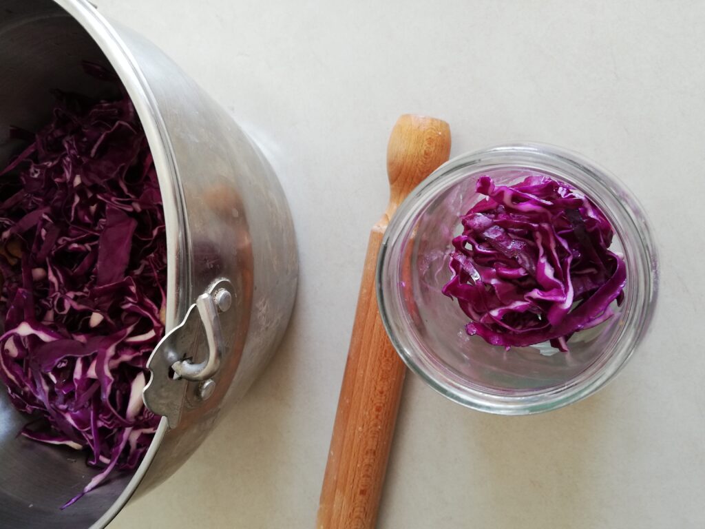 a large pot of shredded red cabbage a rolling pin and a jar half ful with shredded red cabbage