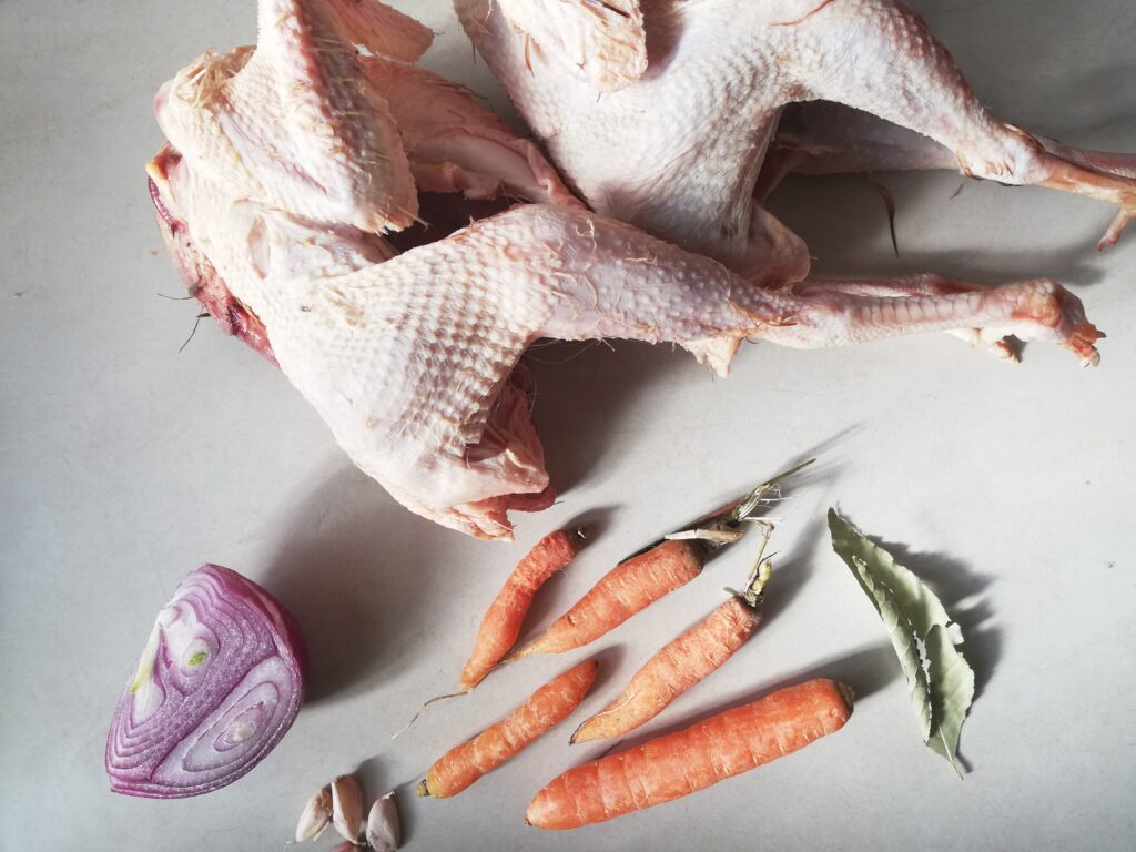 two old hens half onion garlic carrots and bay leaf on a marble countertop
