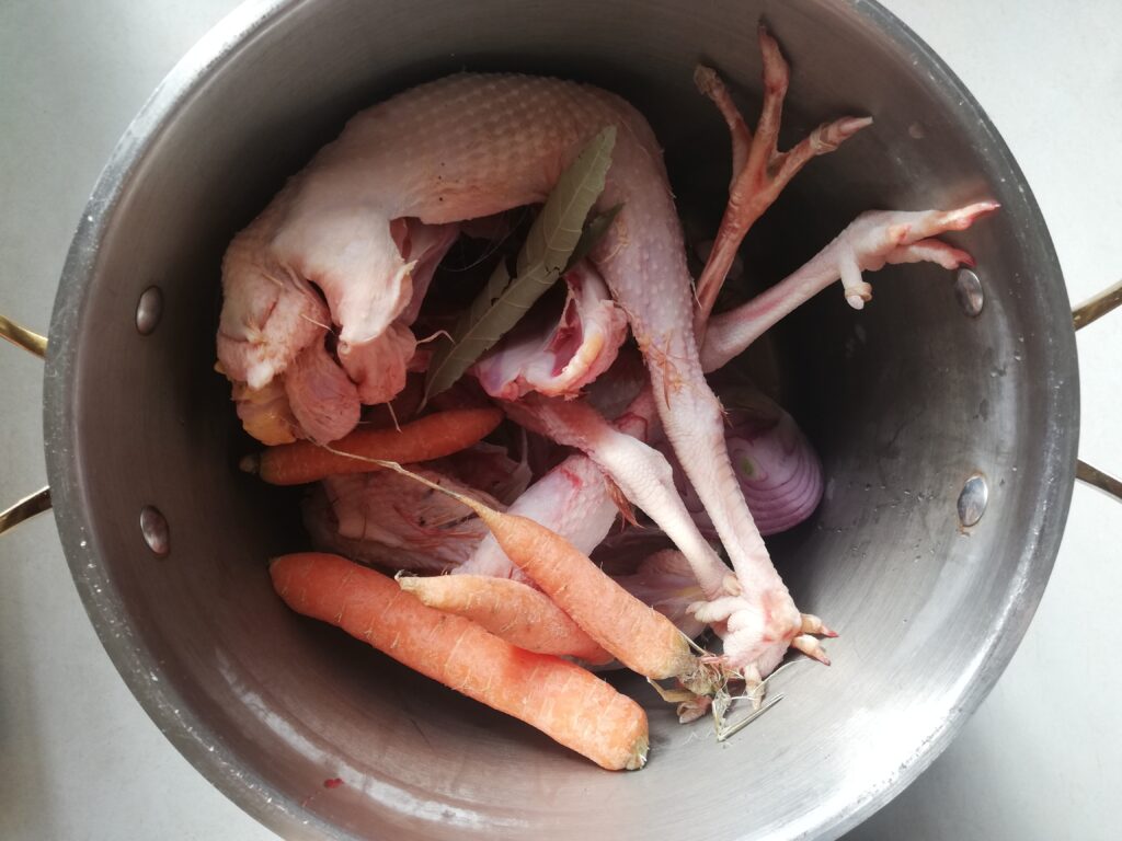 metal stockpot with two old hens bay leaf carrots onion and garlic