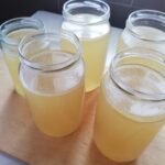 five jars of chicken broth standing on a wooden tray