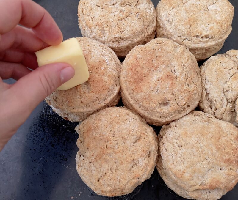 Brushing tops of freshly baked biscuits with butter