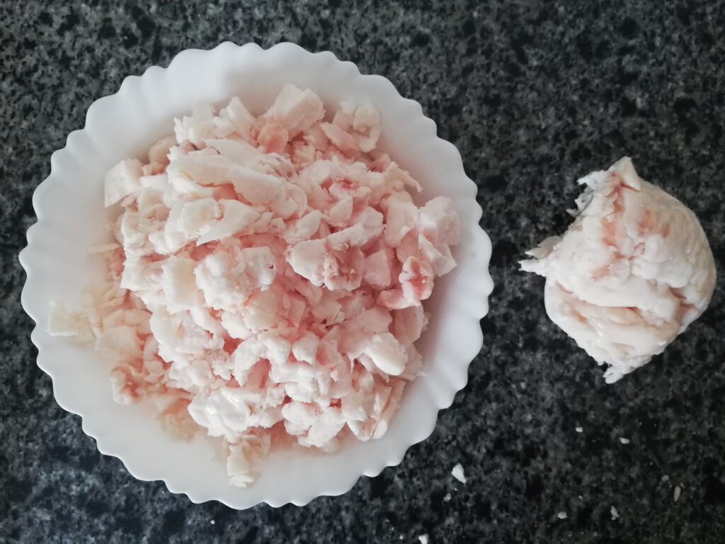 a white bowl full of chopped fat on the left, a lump of fat on the right on a marble counter top