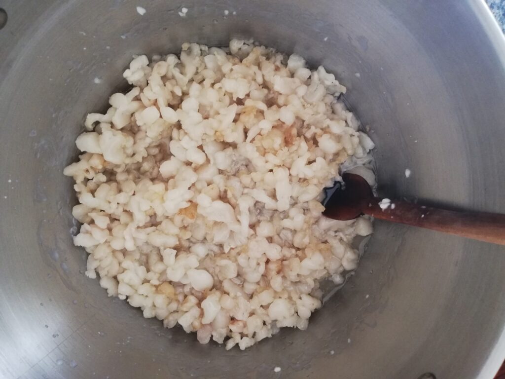 fat rendering in a metal pot with a wooden spoon on the side