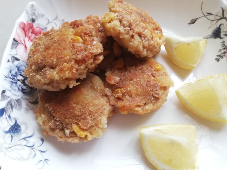 tuna fishcakes with potato on a serving plate with some lemon wedges on the side