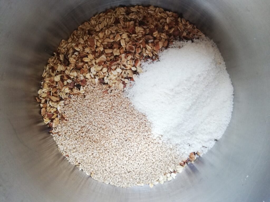 oatmeal sesame seeds chopped walnuts and shredded coconut in a metal mixing bowl