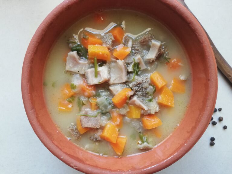 a bowl of tripe soup with carrots and parsley