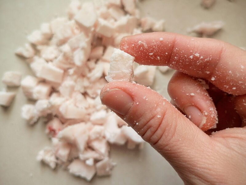 Hand holding a small piece of chopped beef fat