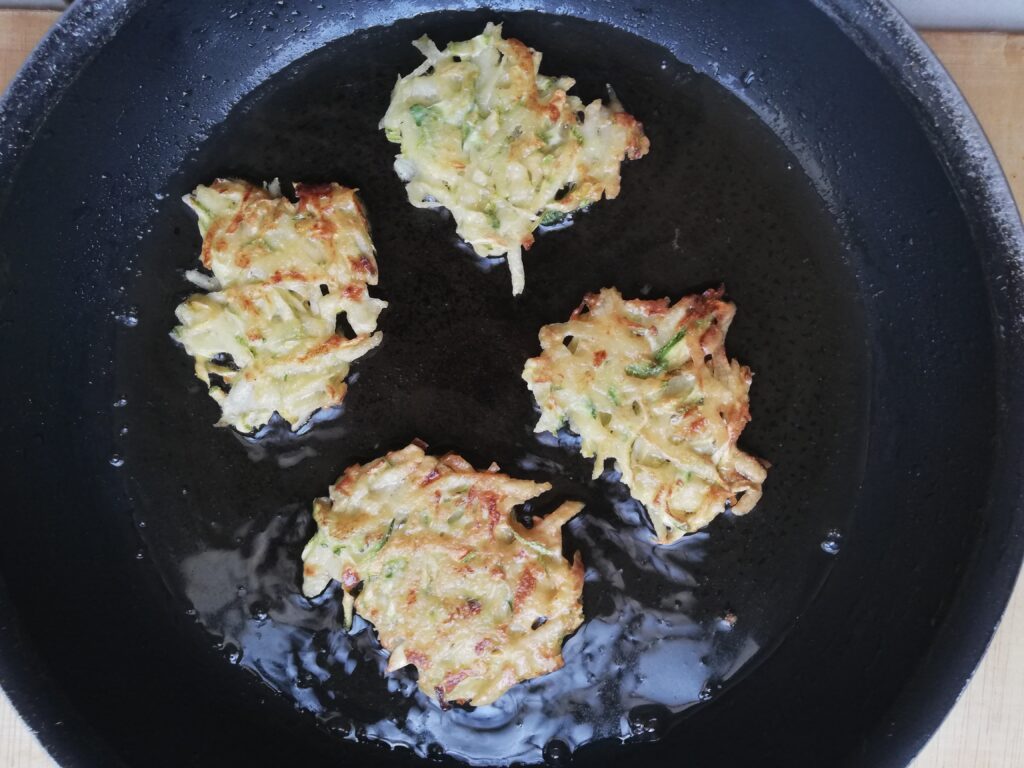crispy zucchini and potato fritters cooking in a frying pan