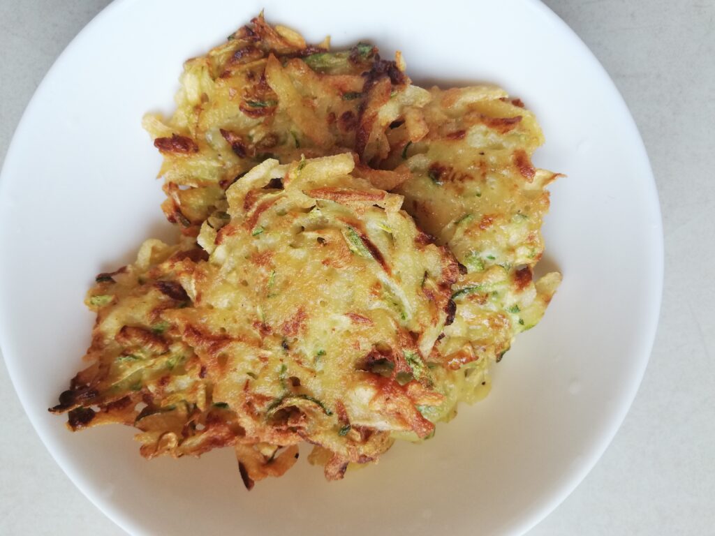 crispy zucchini and potato fritters cooking on a serving plate
