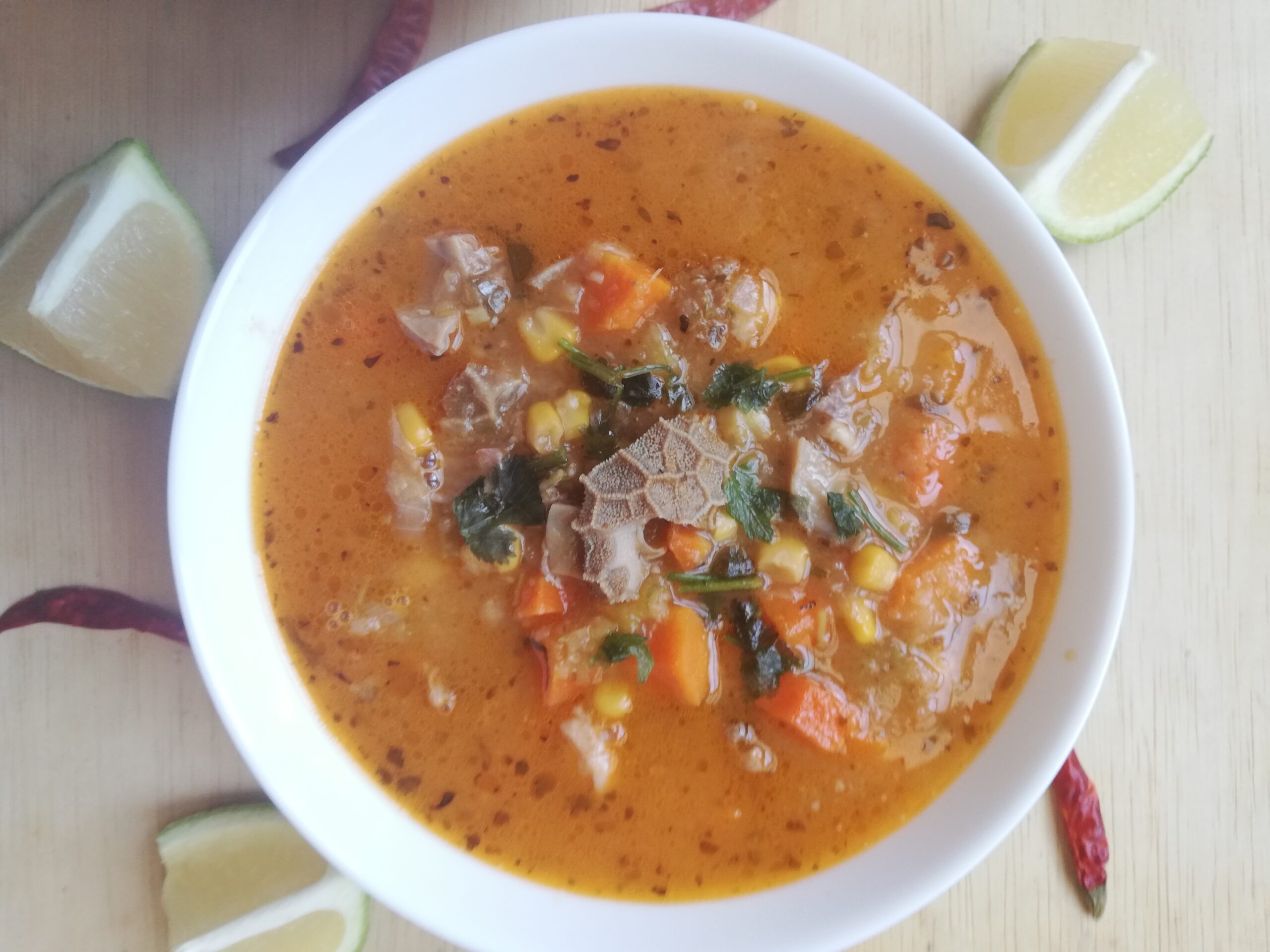 a white bowl of menudo soup garnished with parsley