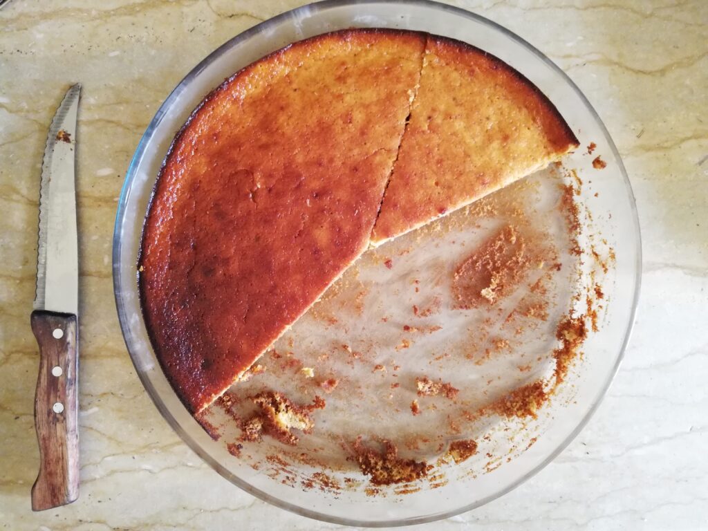 glass pie dish with half of crustless pumpkin pie left and a kitchen knife next to it