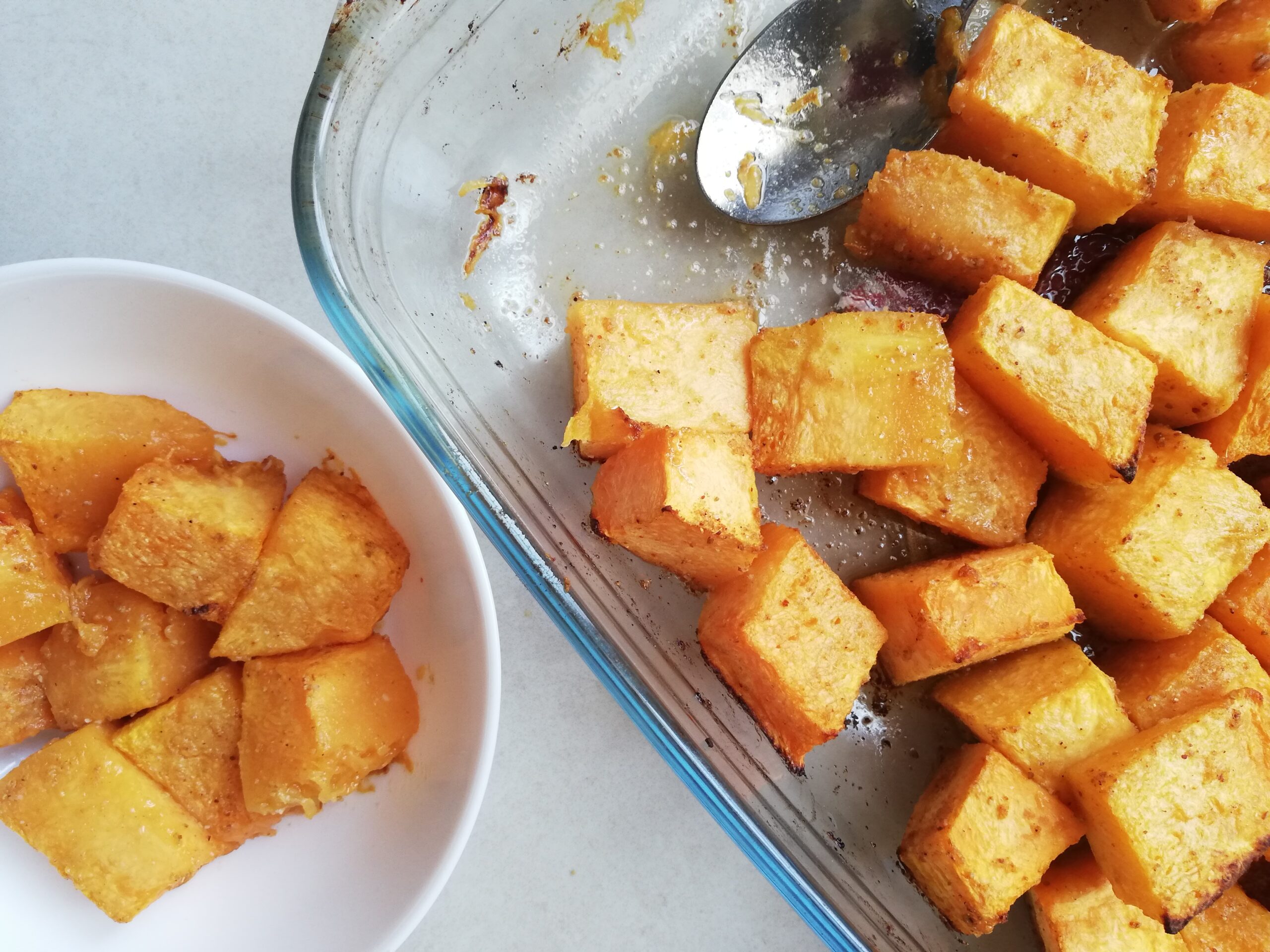glass baking dish with roast pumpkin cubes and a white bowl with roast pumpkin cubes