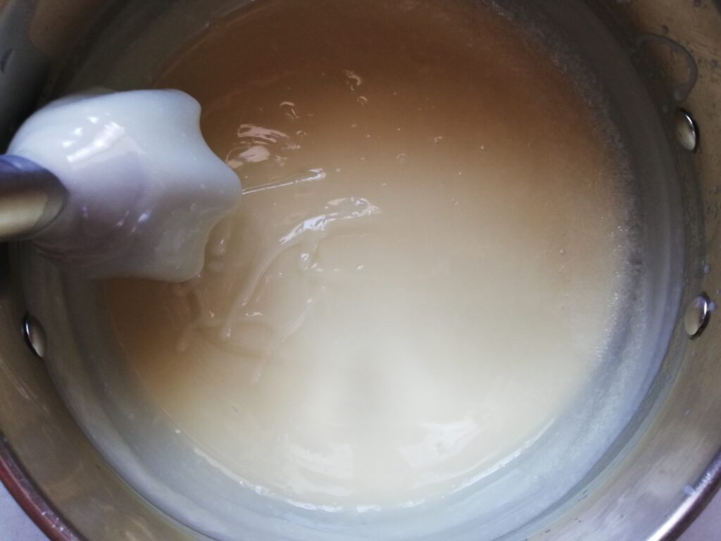 pumpkin spice soap at medium trace in a large metal pot with stick blender making a trace of soap on the surface