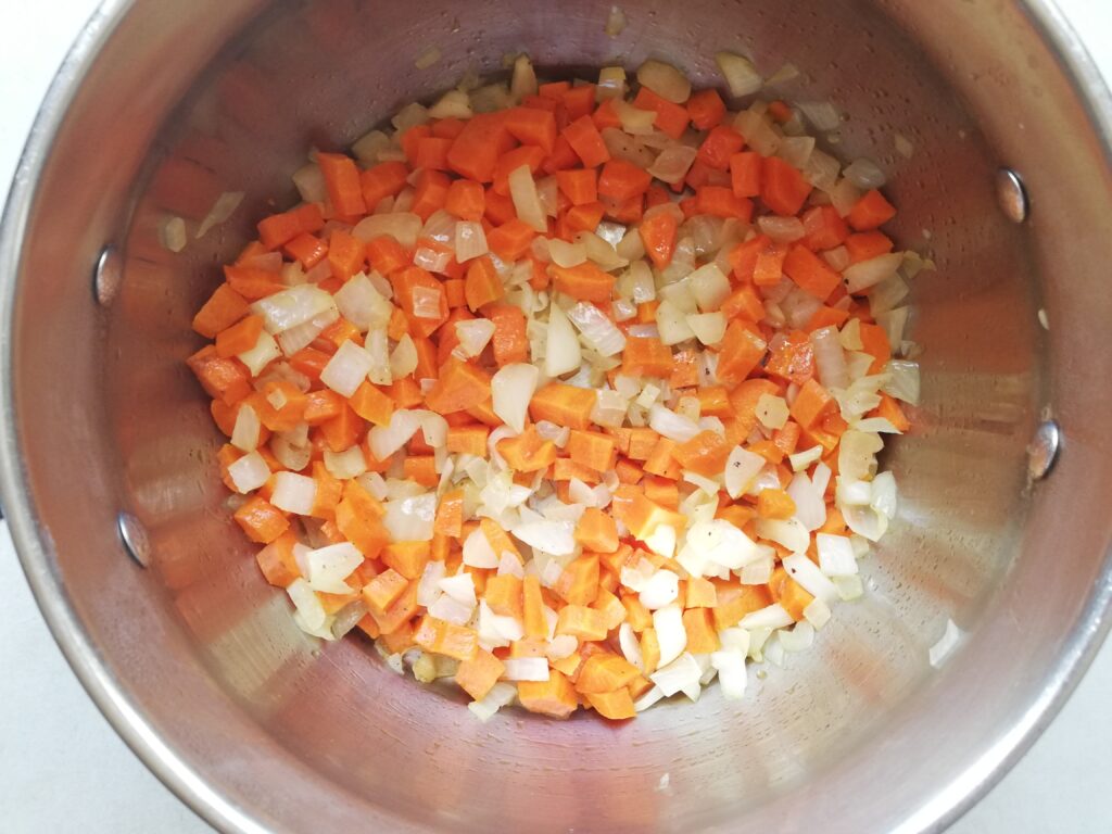 choppped carrots and onions in a metal pot