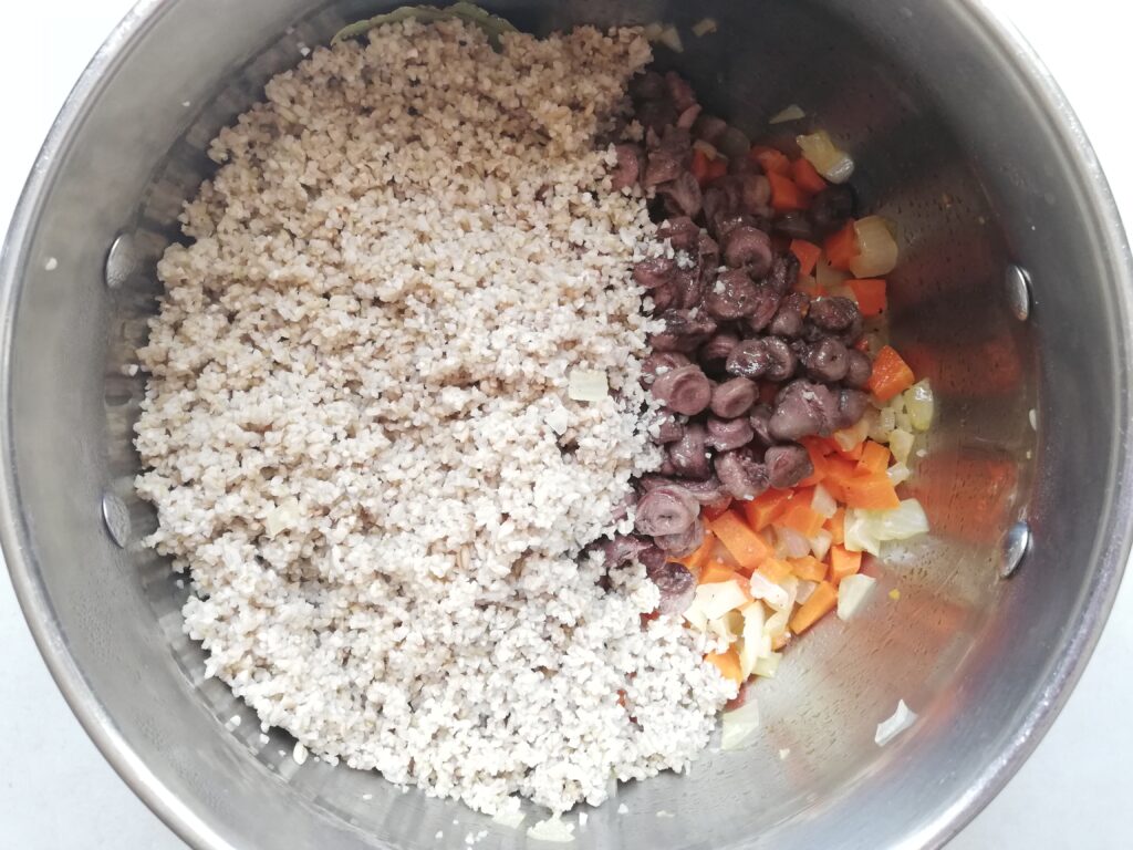 soaked barley chicken hearts carrots and onions cooking in a pot