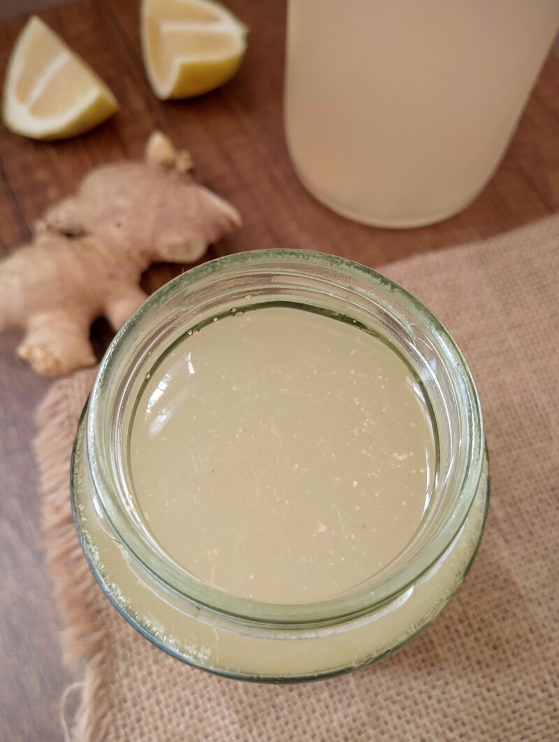 Ginger bug starter in jar on burlap, with ginger root and lemon wedges on the side