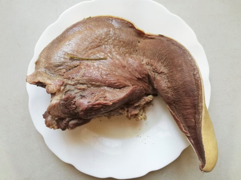Cooked beef tongue cooling on a plate