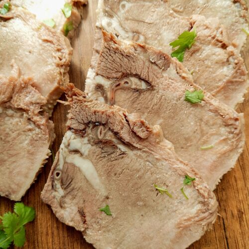 Sliced beef tongue on wooden board