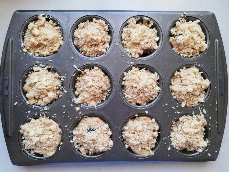 Sourdough applesauce muffins with crumb topping in uffin pan, ready to be baked