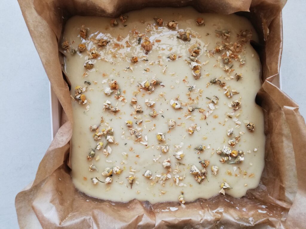 Cold process chamomile soap in the mold sprinkled with chamomile flowers