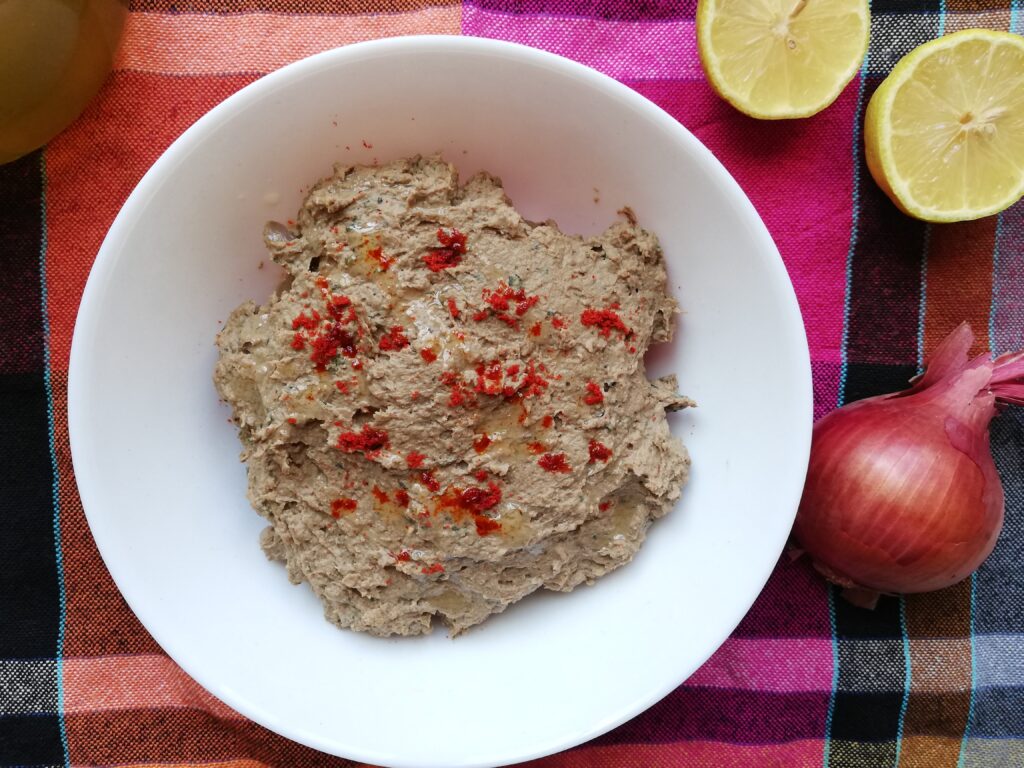 Mexican chicken liver pâté served in a small bowl sprinkled with chilli powder and drizzled with oil