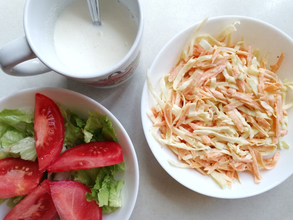 Prepared sides for the kefir fried wings: coleslaw, green salad and garlic sauce