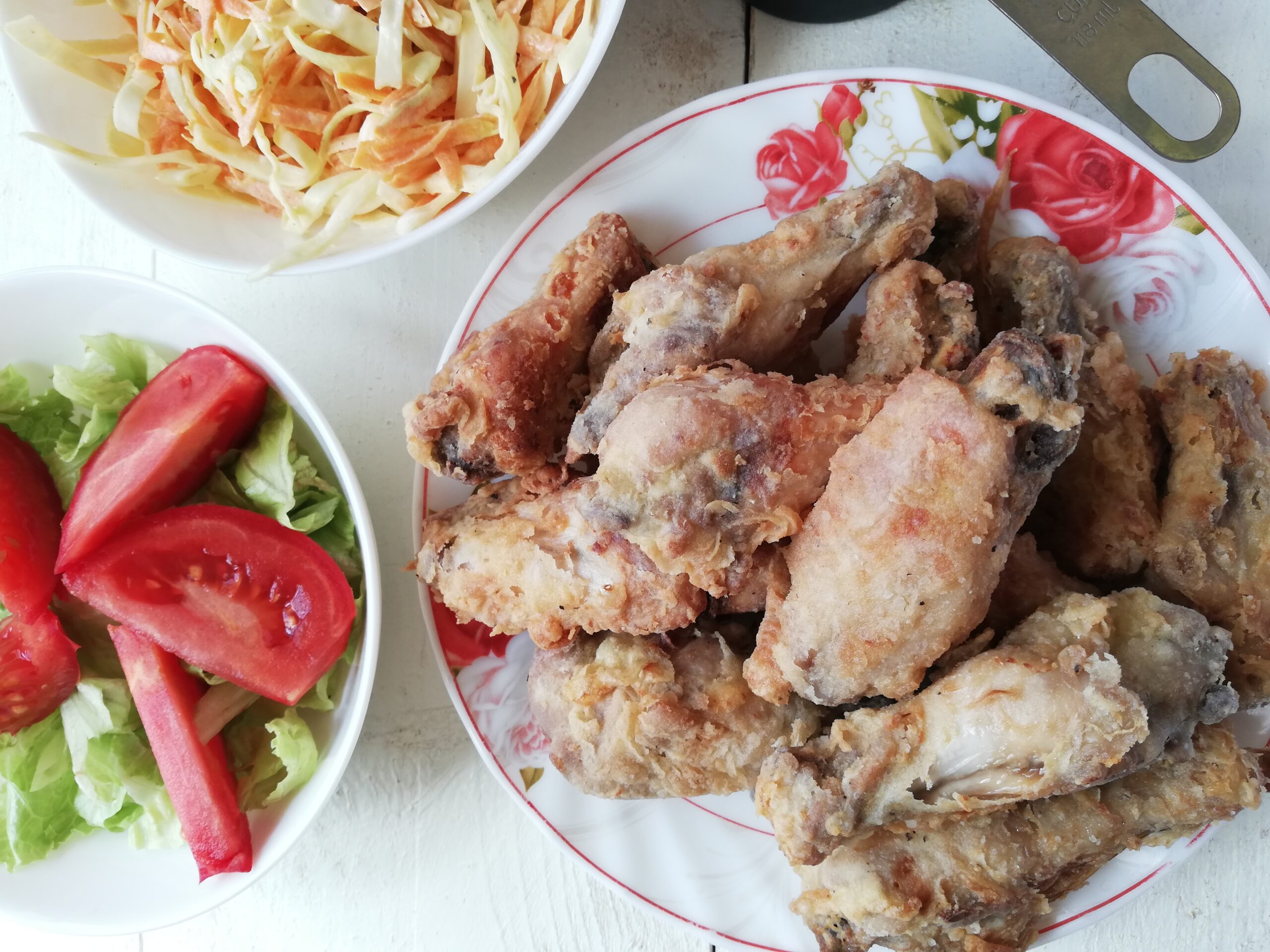 A plate with crispy kefir fried chicken wings a side salad and a dish of coleslaw