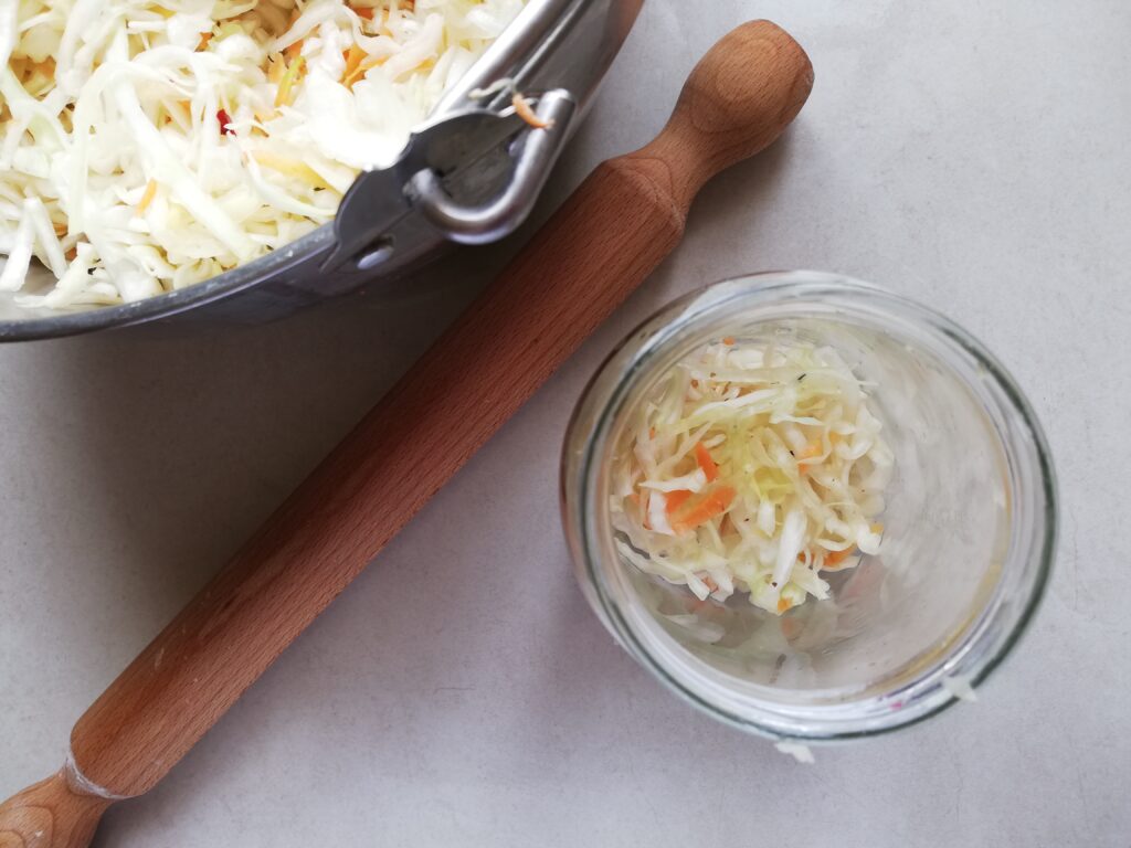 Packing curtido into jars with the help of a rolling pin