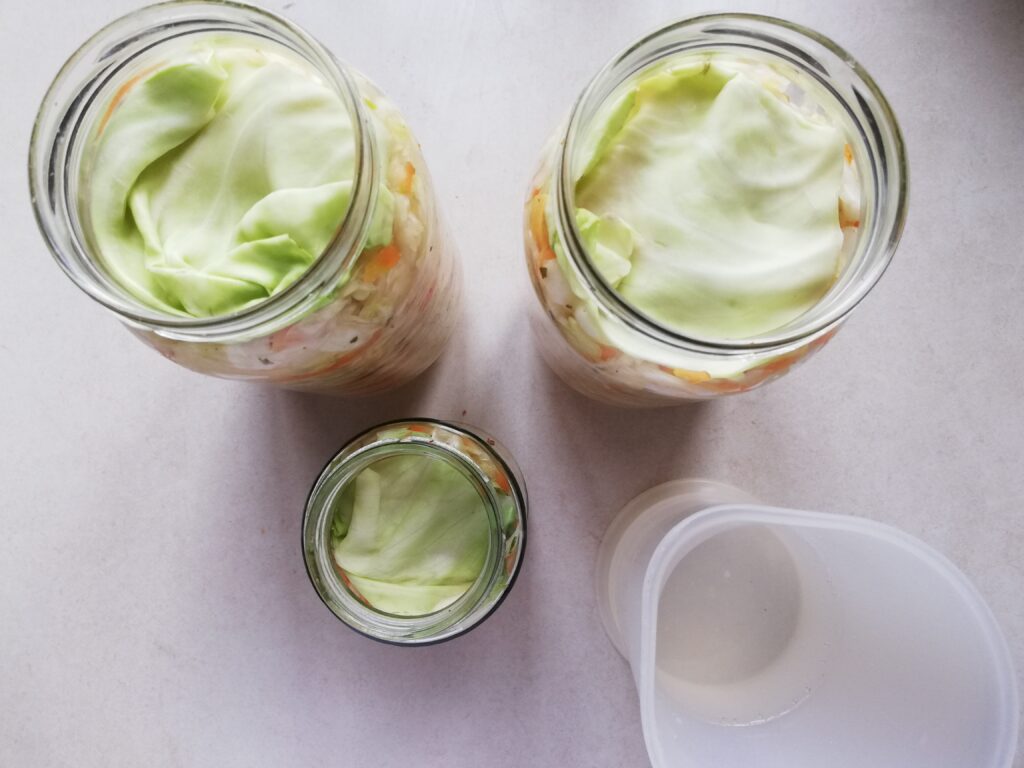 Adding some brine to top off the liquid level in the jars of curtido
